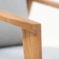 Close-up of outdoor teak armchair showing frame and fabric cushions, highlighting wood texture and weather-resistant design